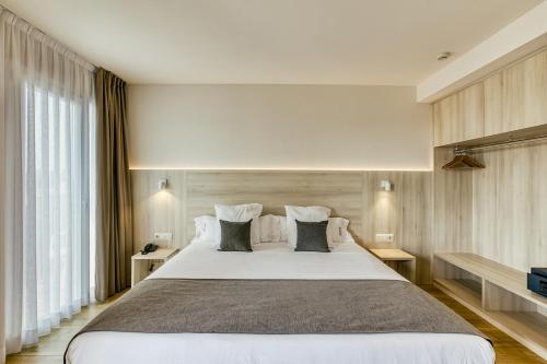 1 dormitorio con 1 cama blanca grande con almohadas en Hotel Emporium - Adults Only, en Castelló d'Empúries