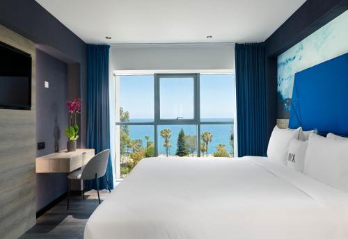a bedroom with a large bed and a large window at NYX Hotel Limassol in Limassol