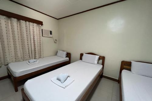 een kamer met 2 bedden met witte lakens bij Tenzai Homestay in Puerto Princesa City