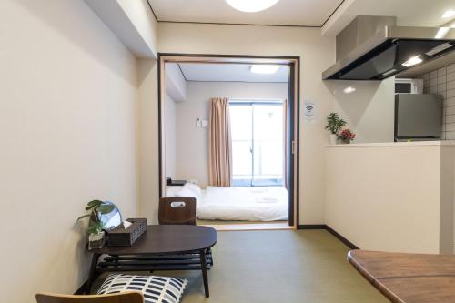 a living room with a table and a bedroom at H2H Tsutenkaku in Osaka