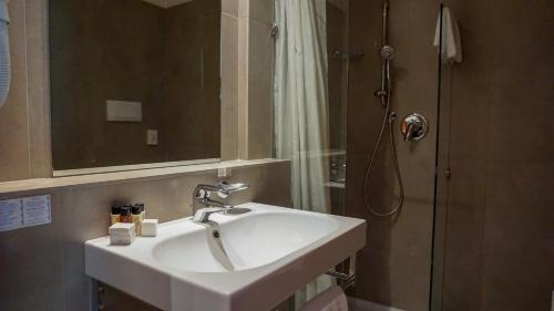 a bathroom with a white sink and a shower at Hotel Mavino in Sirmione