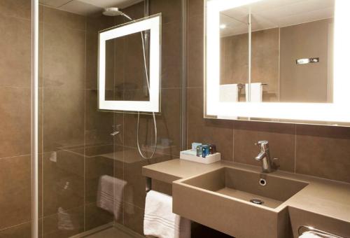 a bathroom with a sink and a shower and a mirror at Novotel Rennes Alma in Rennes
