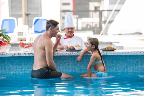 a man and a young girl sitting in the swimming pool at KAY Homes in Ras al Khaimah
