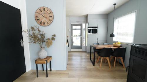 a kitchen and dining room with a clock on the wall at Natuurhuisje LOTUS 