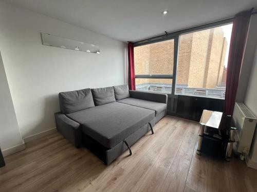 a living room with a couch and a large window at Full Apartment! Brick Lane! in London