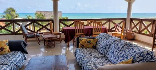 Sala de estar con sofá, mesa y el océano en Guesthouse Bambou Beach en Grand-Popo