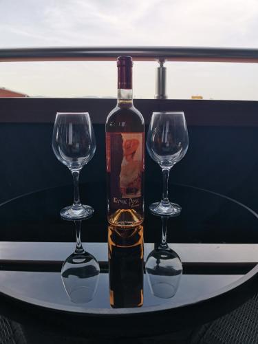 a bottle of wine and two wine glasses on a table at Apartman Luni in Kraljevo