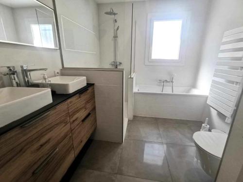 une salle de bain avec deux lavabos et une baignoire et des toilettes dans l'établissement Villa Cinsault, au Cap d'Agde