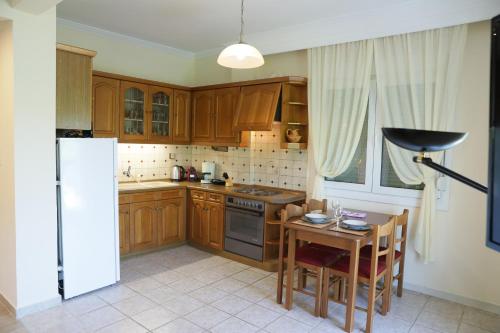 a kitchen with wooden cabinets and a table and a refrigerator at Nana's & Pepi's House in Kastoria