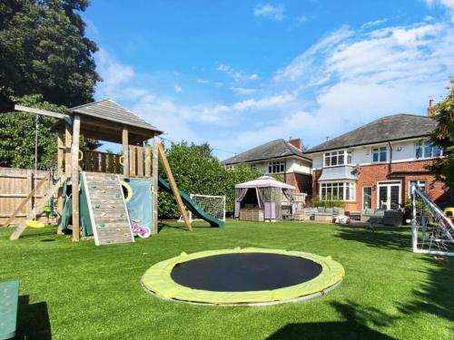 a playground with a slide and a trampoline at Four Bedroom Family Abode with Hot Tub, Garden and BBQ in Bournemouth