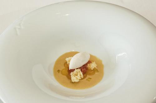 a white plate with a bowl of food with a spoon at Hotel Emporium - Adults Only in Castelló d'Empúries