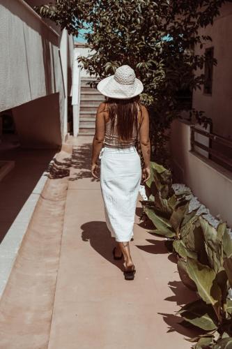 a woman walking down a sidewalk wearing a hat at Om Living Afitos in Afitos