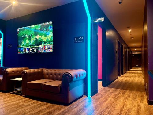 a living room with a couch and a tv on the wall at Arena eSports @ Orchard in Singapore