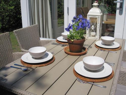uma mesa com tigelas e pratos e uma planta sobre ela em De Zeemeeuw em Egmond aan den Hoef