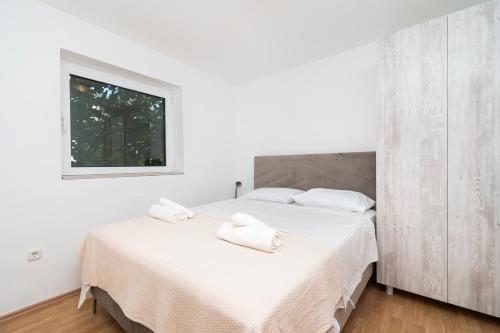 1 dormitorio blanco con 1 cama con 2 toallas en Rimagis Apartments, en Žaborić