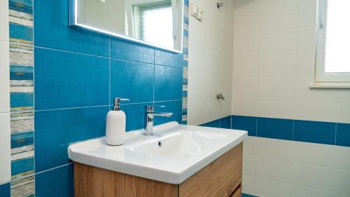 ein Badezimmer mit einem weißen Waschbecken und blauen Fliesen in der Unterkunft Calma apartments in Trogir