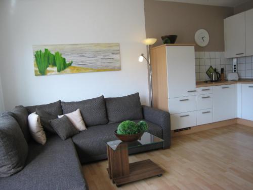 een woonkamer met een grijze bank en een keuken bij 2 min zum Strand in Borkum