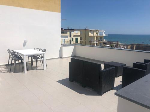 Un balcón con mesa y sillas y el mar. en suite scauri-inn, en Scauri
