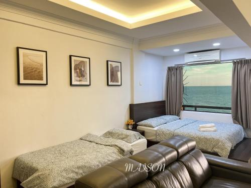 a bedroom with two beds and a couch and a window at The Corus Suites Port Dickson By MAISON in Port Dickson