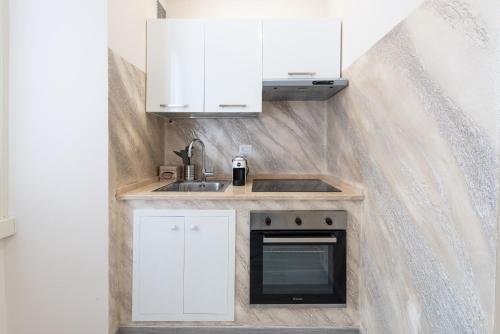 una piccola cucina con armadi bianchi e lavandino di Ancient Rome Apartment a Roma