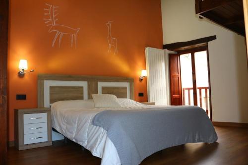 a bedroom with a bed with an orange wall at Apartamentos Turísticos Accesibles La Quinta de Sotoscueva in Quintanilla del Rebollar