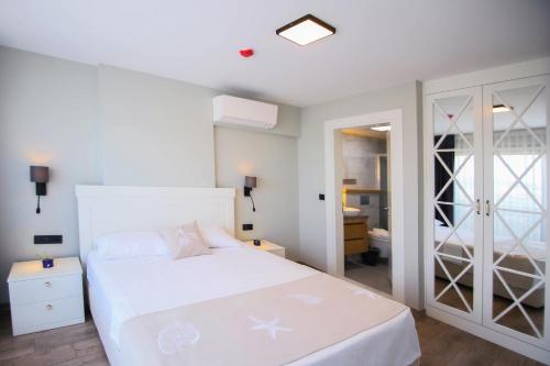 a bedroom with a white bed and a bathroom at Krem Marin Otel in Cesme