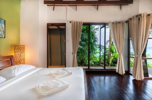 a bedroom with a bed and a large window at Captain Hook Resort @Koh Kood in Ko Kood