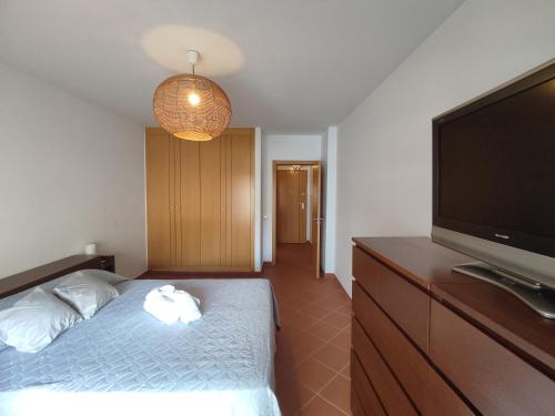 1 dormitorio con 1 cama y TV de pantalla plana en 3H Terrace - Casas & Papéis, en Armação de Pêra