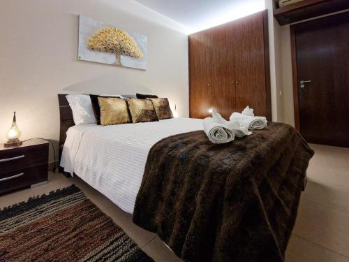1 dormitorio con 1 cama grande y 2 toallas. en Apartamentos Herdade dos Salgados, en Albufeira