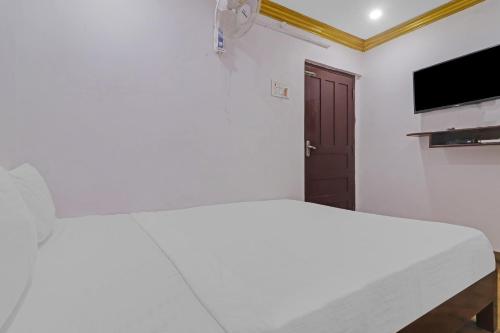 a white bedroom with a bed and a flat screen tv at Guest Inn Near Hyderabad Central in Hyderabad