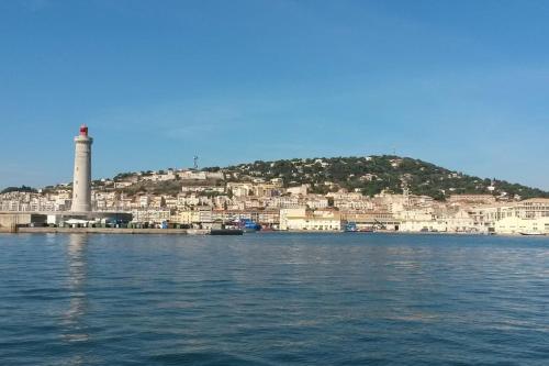 une vue d'une ville depuis l'eau avec un phare dans l'établissement Escapade à la plage de Sète, à Sète