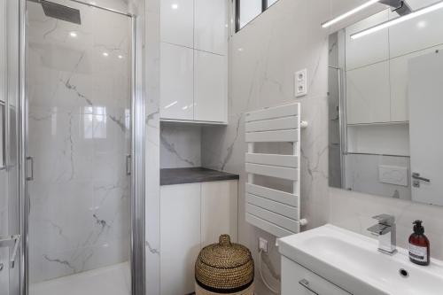 uma casa de banho branca com um chuveiro e um lavatório. em Le Rez de Plage - Appt pour 4 vue mer et proche des plages em Saint Malo