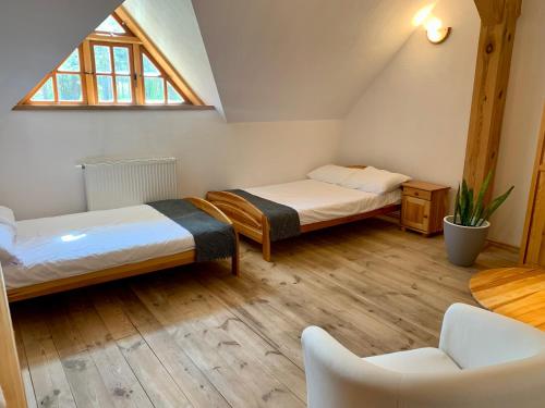 a attic room with two beds and a chair at Gościniec Rzemyk in Wdzydze Kiszewskie