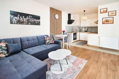 a living room with a blue couch and a table at Symphony City Square Aparthotel in Wrocław