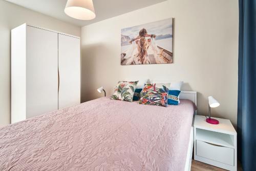 a bedroom with a pink bed and a picture on the wall at Symphony City Square Aparthotel in Wrocław