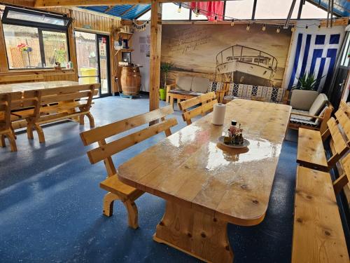 a large wooden table in a room with benches at Casuta Noastra - Sulina in Sulina