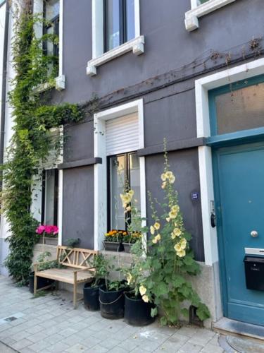 un bâtiment avec une porte bleue, des plantes et un banc dans l'établissement Studio Dageraad, à Anvers