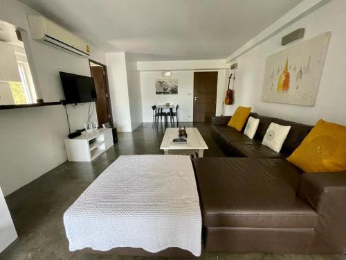 a living room with a brown couch and a table at Spacious Apartment by the Sea in Bang Rak Beach