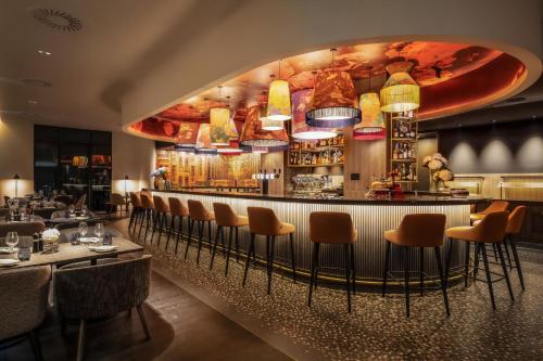 um restaurante com um bar com cadeiras e mesas em Marriott Executive Apartments Brussels em Bruxelas