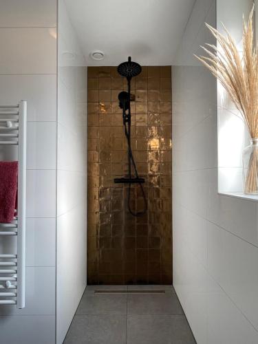 een douche in een badkamer met een tegelwand bij Luxe Vakantiehuis Vosje op de Veluwe Nunspeet in Nunspeet