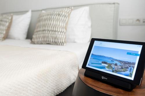 a tablet computer sitting on a table next to a bed at Paros Agnanti Resort & Spa in Parikia