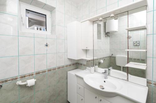 Baño blanco con lavabo y espejo en Rimagis Apartments en Zaboric