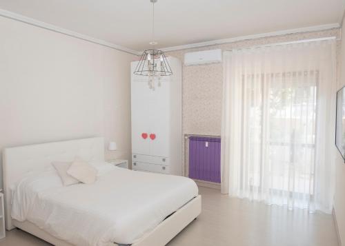 Un dormitorio blanco con una cama blanca y una ventana. en DOMUS LUNA, en Sorrento