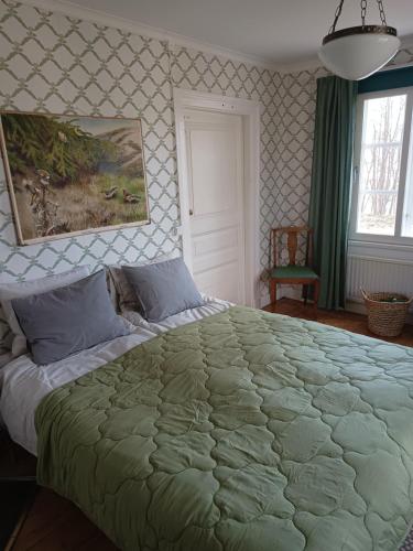 a bedroom with a large bed with a green blanket at Sparreholm Bed and Breakfast in Sparreholm
