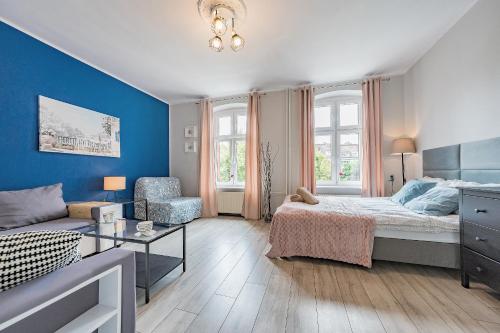 a bedroom with blue walls and a bed and a couch at Apartament Przytulny z 2 sypialniami na Starym Mieście/ 2bedrooms Old Town in Gdańsk