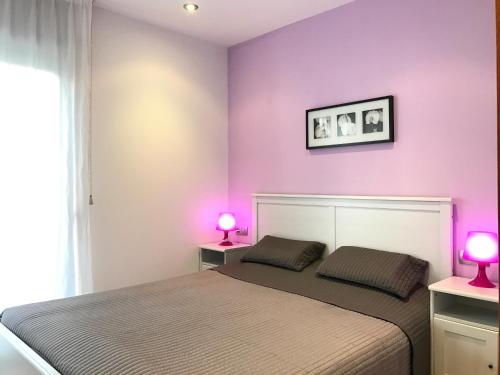 リョレート・デ・マルにあるLloret Beach Apartments - SeaViewの紫の壁のベッドルーム1室、ベッド1台(ランプ2つ付)