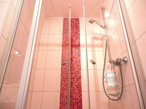 a shower with a glass door with a red mosaic shower curtain at Gästezimmer / Weingut Peter in Wachenheim an der Weinstraße