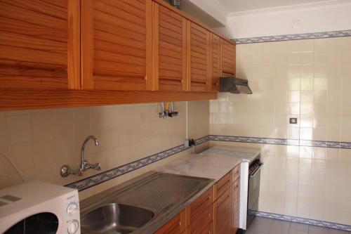 a small kitchen with wooden cabinets and a sink at Sesimbra Flat in Sesimbra
