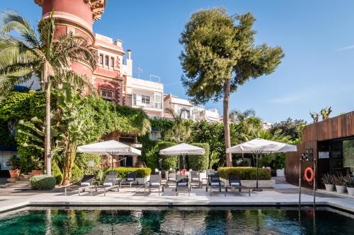 a pool with chairs and umbrellas in front of a building at Hotel Medium Sitges Park in Sitges