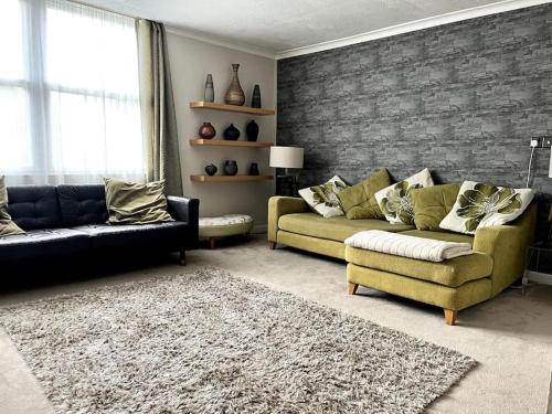 a living room with two couches and a brick wall at Riverside Apartment in Uny Lelant